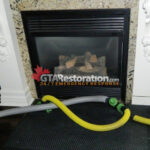 Yellow air hose positioned beside a fireplace