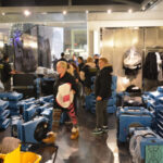Restoration crew surrounded by blue drying equipment in a shop corridor.