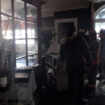 Restoration workers beside a glass shop entrance.
