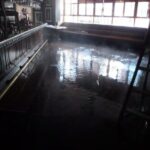Floodwater reflecting windows across an empty room.