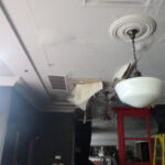 Damaged ceiling around a hanging light fixture.