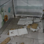 Broken ceiling material on a tiled floor beside a glass door.