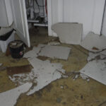 Large broken wallboard pieces covering a tiled floor.