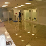 Standing water reflecting ceiling lights in a large commercial room.