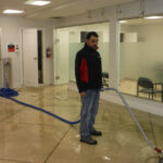 Restoration worker holding a blue hose in a bright commercial space.