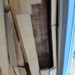 Removed floorboards exposing the layer beneath beside a window.
