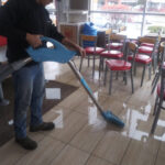 Restoration worker extracting water from a tiled cafe floor.