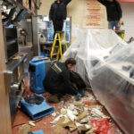 Restoration crew working near an open ceiling and a plastic-covered counter.