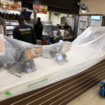 Restoration workers behind a counter protected with plastic sheeting.