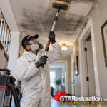 Restoration technician cleans smoke residue from a ceiling with an extension tool.