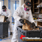 Two restoration technicians remove damaged cabinetry after a kitchen fire.