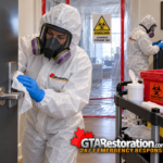Protected technicians wipe a door handle and stair railing near a biohazard containment barrier.