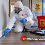 Technician swabs a cleaned floor edge beside a handheld hygiene monitoring device.
