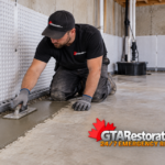 GTA Restoration workers install foundation drainage membrane and a footing drain outside a brick home.